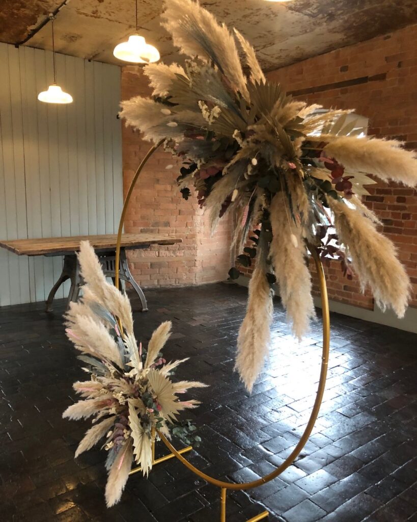 shining light on brick work where shiny with footsteps of hundreds of weavers. a circular dried flower display with pampas. boho style