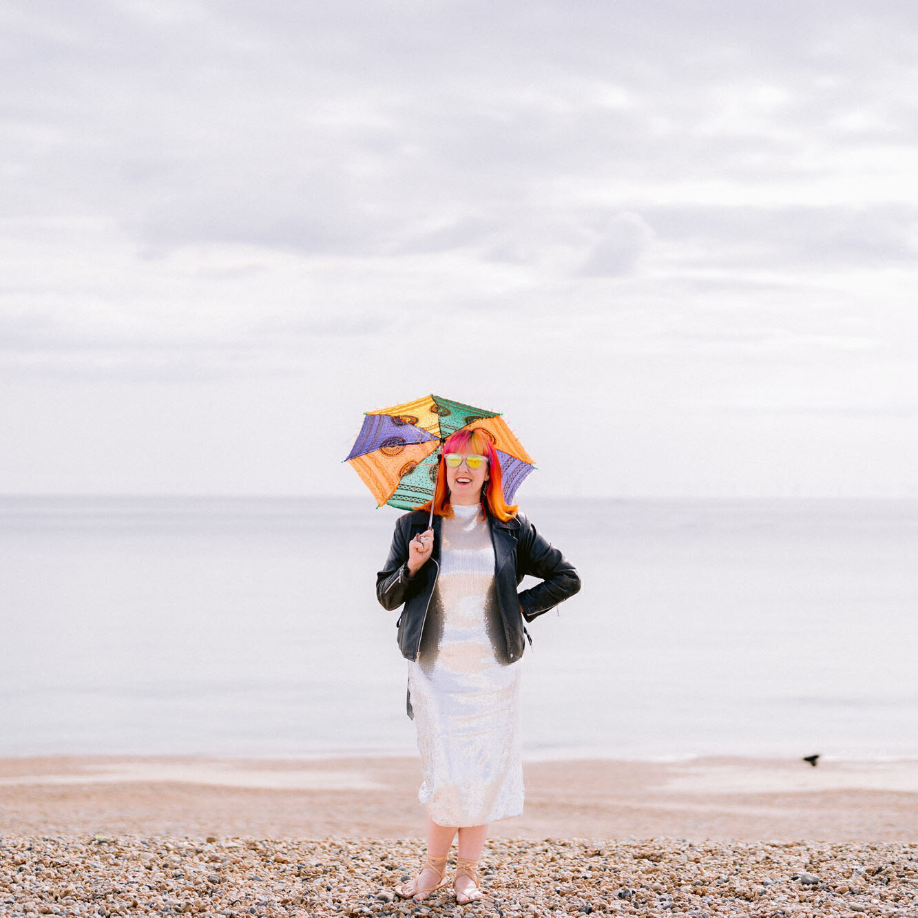 Jess May on Brighton Beach holding an umbrella