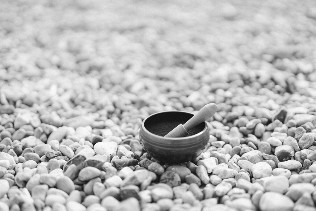 a black and white photo of a nepalese singing bowl on a pebble beach in Brighton